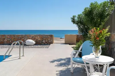 a patio with a table and chairs and the ocean at The Rhodes South Escape Beach in Plimmiri
