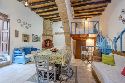a kitchen and living room with a table and chairs at Maison Lemonia in Lardos