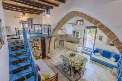a living room with a spiral staircase and a table at Maison Lemonia in Lardos
