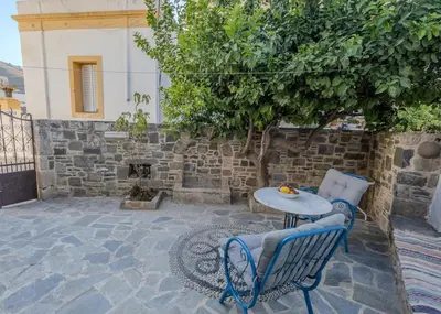 a patio with two chairs and a table and a tree at Maison Lemonia in Lardos