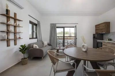a living room with a table and chairs and a kitchen at Zàia Suites & Living, Suite N2, pool view in Gennadi