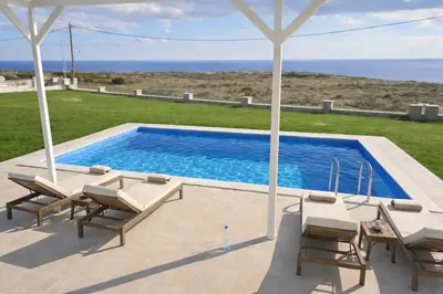 a swimming pool with chairs and a view of the ocean at Kalithea Sunrise in Rhodes Town
