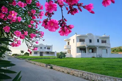 a large white house with pink flowers in the foreground at Kalithea Sunrise in Rhodes Town