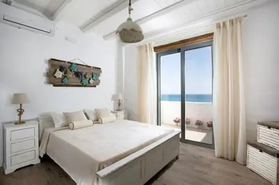 a white bedroom with a bed and a large window at Axiotheaton Villa Lydia in Pefki Rhodes