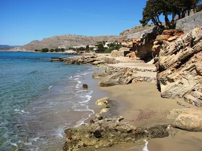a beach with rocks and the water and trees at Axiotheaton Villa Lydia in Pefki Rhodes