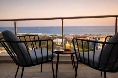 a balcony with two chairs and a candle on a table at Alkion in Asgourou