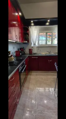 a kitchen with red cabinets and a sink at Louloudakis Apartment in Koskinou