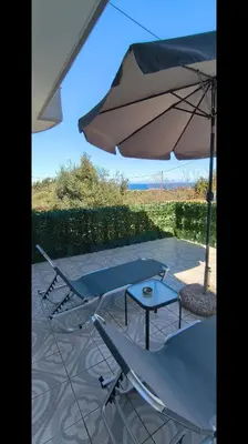 two chairs and a table and an umbrella at Louloudakis Apartment in Koskinou