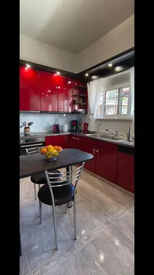 a kitchen with red cabinets and a table with fruit on it at Louloudakis Apartment in Koskinou