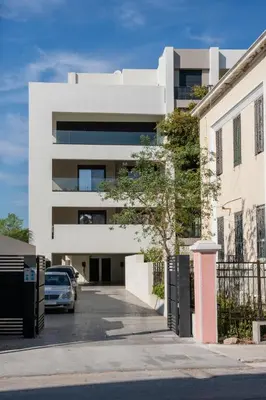 a white building with a car parked in a parking lot at SunHall City Maisonette in Rhodes Town