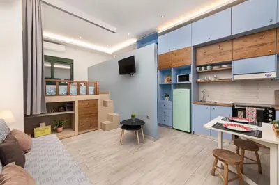 a kitchen and living room with blue cabinets and a table at Loft 146 in Rhodes Town