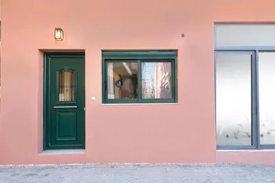 a pink building with a green door and windows at Loft 146 in Rhodes Town