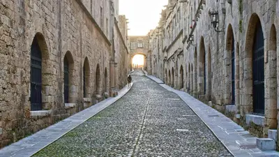 an alley between two stone buildings with the sun setting at Loft 146 in Rhodes Town