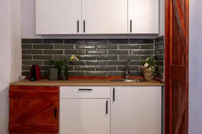 a kitchen with white cabinets and a brick wall at St Nicholas traditional house in Rhodes Town