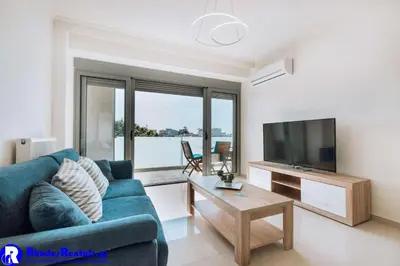 a living room with a blue couch and a tv at Rhodes Port Haven Suite in Rhodes Town