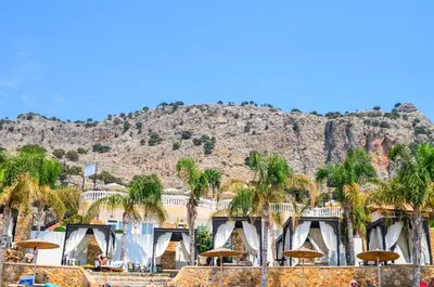 a resort with palm trees and a mountain in the background at Coralli Apartments in Pefki Rhodes
