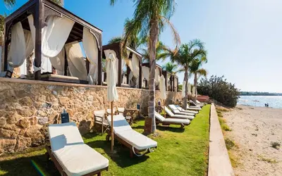 a row of chairs and umbrellas on the beach at Coralli Apartments in Pefki Rhodes