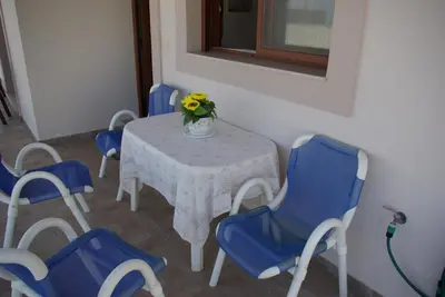 a table with blue chairs and a vase of flowers on it at Mano's House in Monólithos
