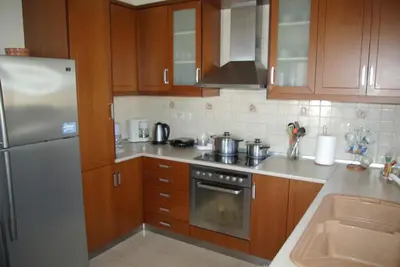 a kitchen with wooden cabinets and a stainless steel refrigerator at Mano's House in Monólithos