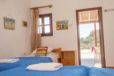 a bedroom with two beds and a door to a balcony at Jacks Studios in Líndos