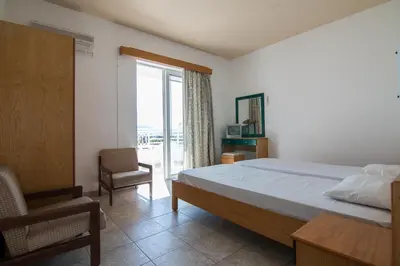 a bedroom with a bed and a chair and a window at Faliraki Dream Studios & Apartments in Faliraki