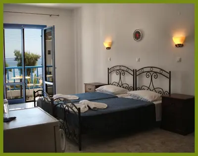 a bedroom with two beds and a balcony at Hotel Eleni Beach in Livadia