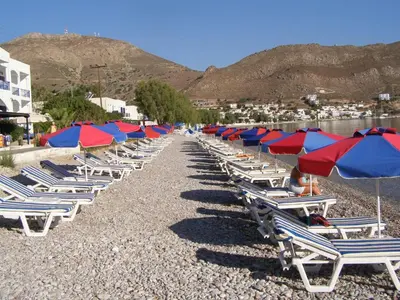 a row of lounge chairs and umbrellas on a beach at Hotel Eleni Beach in Livadia