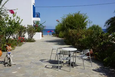 a table and chairs on a patio with a bike at Hotel Eleni Beach in Livadia