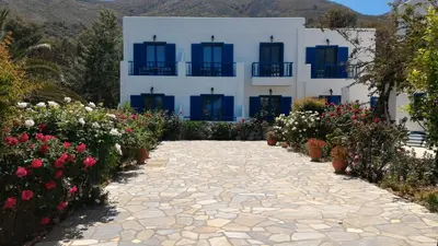 a building with blue windows and flowers in front of it at Hotel Eleni Beach in Livadia