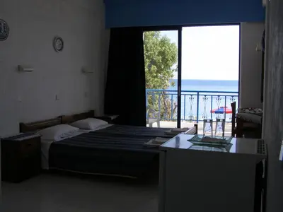 a bedroom with a bed and a view of the ocean at Hotel Eleni Beach in Livadia