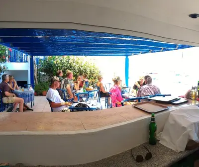 a group of people sitting at tables in a restaurant at Hotel Eleni Beach in Livadia