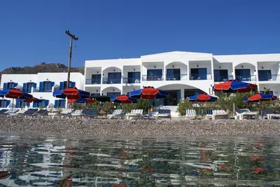 a hotel on the beach with chairs and umbrellas at Hotel Eleni Beach in Livadia