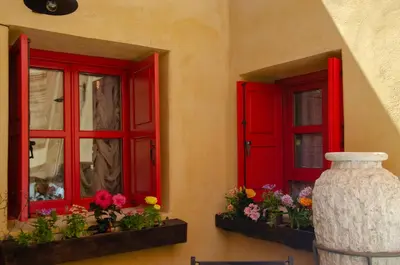 two red windows with flowers and a vase in front of them at Elafusa Luxury Apartment in Rhodes Town