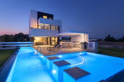 a villa with a swimming pool at night at Albatross Beach Front Villas in Gennadi