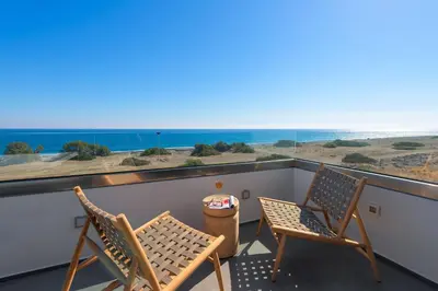 two chairs on a balcony with a view of the beach at Albatross Beach Front Villas in Gennadi