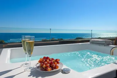 a glass of champagne and a plate of fruit next to a hot tub at Albatross Beach Front Villas in Gennadi