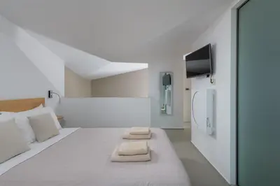 a white room with a bed with two towels on it at Albatross Beach Front Villas in Gennadi