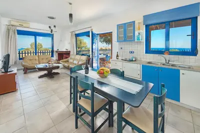 a kitchen with blue cabinets and a table with chairs at Stegna House Sea View in Archangelos