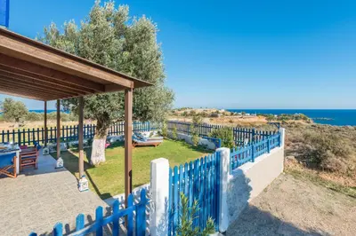a blue fence in front of a house with the ocean at Stegna House Sea View in Archangelos