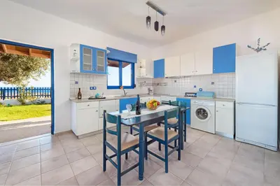 a kitchen with blue cabinets and a table with chairs at Stegna House Sea View in Archangelos