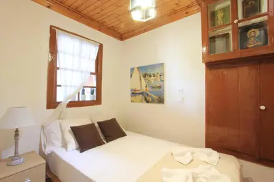 a bedroom with a white bed and a window at Athanasia's House in Symi
