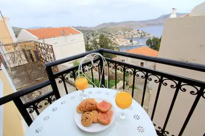 a table with a plate of food and two glasses of orange juice at Athanasia's House in Symi
