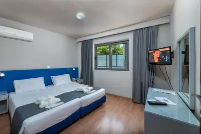 a bedroom with a large bed with a tv on it at 7Palms in Rhodes Town