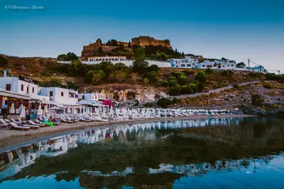 a view of a beach with chairs and buildings at Lindos Shore Summer House with Jacuzzi and sea view !!! in Líndos