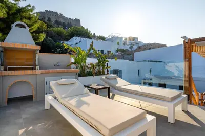a balcony with two beds and a fireplace at Lindos Shore Summer House with Jacuzzi and sea view !!! in Líndos