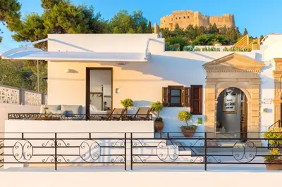 a house with a balcony with a castle in the background at Lindos Shore Superior Studio in Líndos