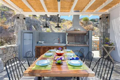 a wooden table and chairs on a patio with a kitchen at Lindos Vigli Private Villa in Líndos