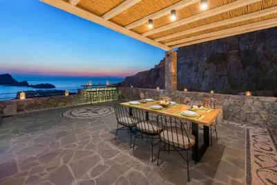 a patio with a table with chairs and a view of the ocean at Lindos Vigli Private Villa in Líndos