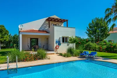 a villa with a swimming pool in front of a house at Athena Villa in Kolimbia