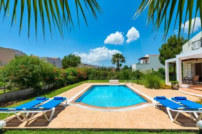 a swimming pool in a yard with chairs and a house at Apollo Villa in Kolimbia